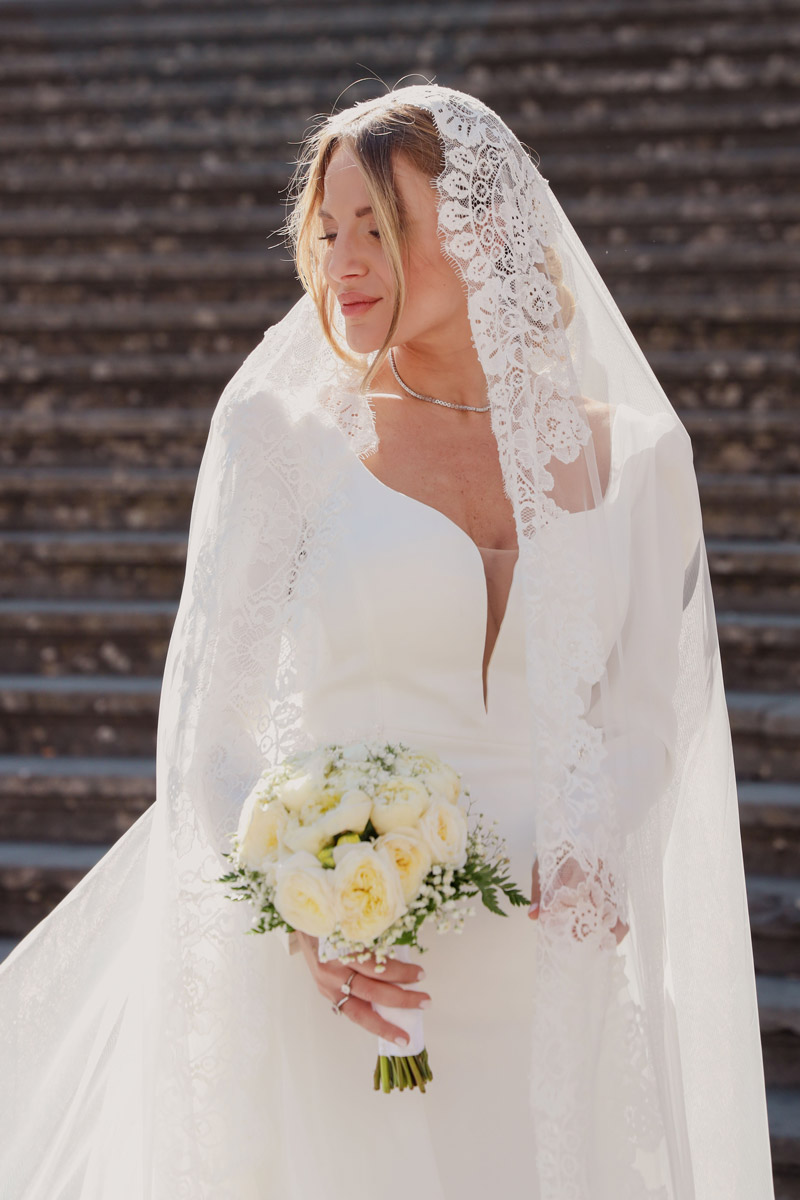 Sposa con velo lungo in pizzo e bouquet bianco sulla scalinata, fotografo matrimonio Salerno