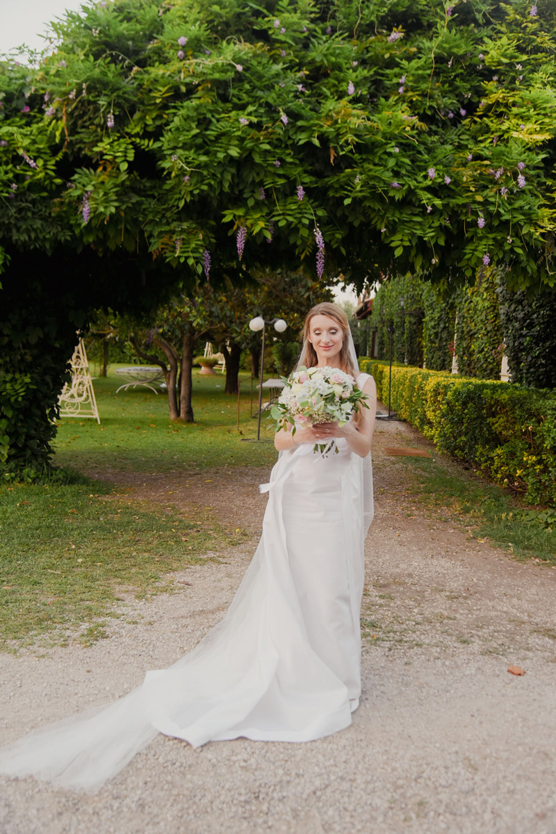 Sposa nel giardino con glicine in fiore, matrimonio elegante in Campania