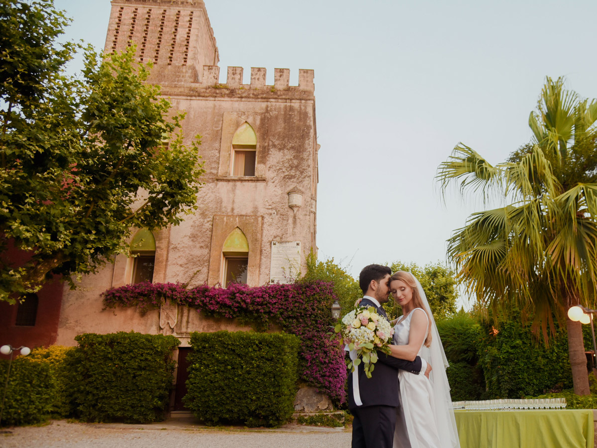 Sposi abbracciati davanti a una villa storica con torre, matrimonio in Campania