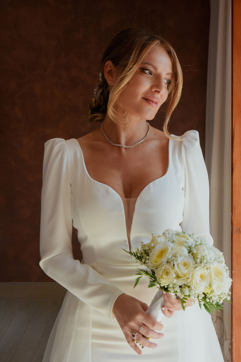 Sposa elegante alla luce della finestra con bouquet bianco, fotografo matrimonio Costiera Amalfitana