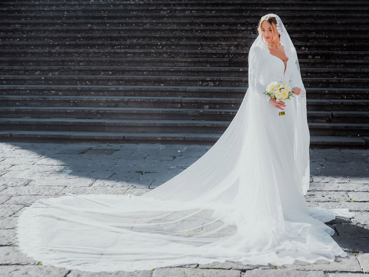 Sposa con lungo velo disteso a terra davanti alla scalinata, matrimonio vista mare Salerno