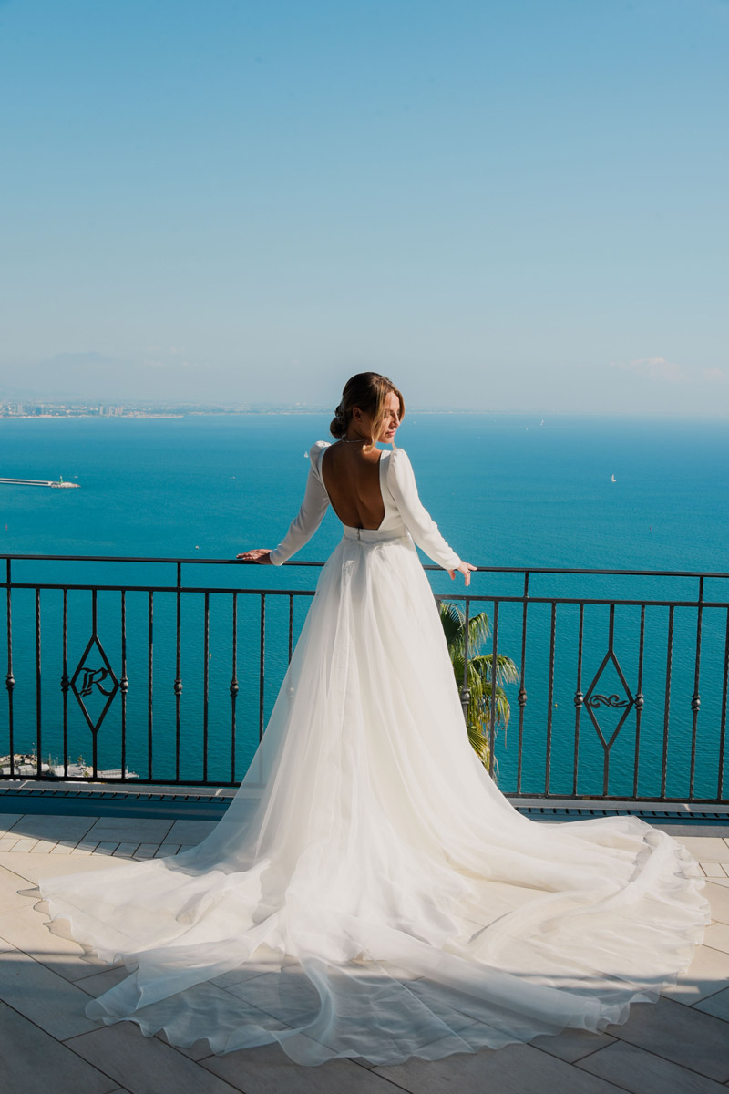 Sposa di spalle con strascico aperto sulla terrazza affacciata sul golfo di Salerno, matrimonio vista mare Campania