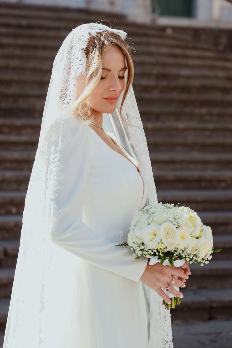 Ritratto di sposa con velo in pizzo e bouquet di rose bianche, matrimonio elegante Costiera Amalfitana