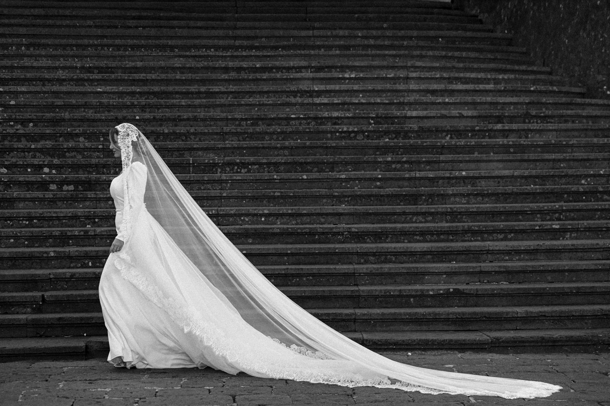 Sposa con velo cattedrale disteso in bianco e nero sulla scalinata, fotografo matrimonio Campania